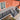 Outdoor deck with black railing and steps leading to a house with orange siding.