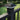 Black solar post cap light on a fence post with green grass and bushes in the background #color_black
