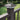 Dark gray solar post cap light on a wooden post with green grass and bushes in the background #color_weathered-brown
