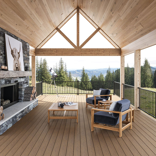 Composite deck with outdoor furniture and fireplace, surrounded by a scenic view of trees and mountains