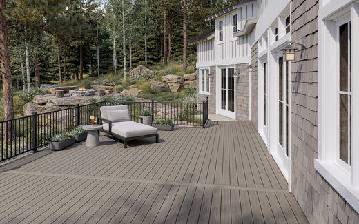 Composite deck with outdoor furniture in front of a house with a forest background