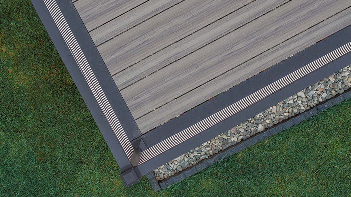 Close-up corner of a deck in Deckorators Voyage Decking in Sierra with Picture Frame Board in Dark Slate #color_dark-slate