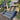 Outdoor composite deck steps leading up a slope from a dirt yard to a raised deck, with trees on both sides and a house in the background.