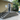 A set of outdoor concrete composite deck stairs with a black metal railing, installed on a raised gray wood deck in front of a beige stucco house.