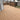 Composite decking planks in a warm brown tone installed on a residential deck, with a black metal railing and a wooden fence in the background.